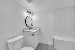 Bathroom featuring tile floors, a textured ceiling, vanity, and toilet