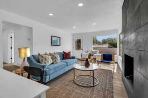 Living room featuring a tiled fireplace, a textured ceiling, and dark wood-type flooring