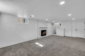 Unfurnished living room featuring dark carpet, a large fireplace, and a textured ceiling