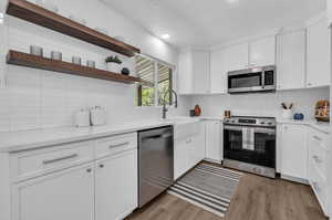 Kitchen with stainless steel appliances, hardwood / wood-style flooring, and backsplash