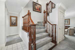 Stairway with tile floors and crown molding