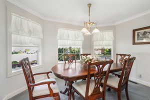 Large dining space featuring a healthy amount of sunlight, ornamental molding, and an inviting chandelier