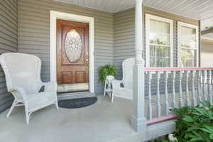 Stained glass front doorway featuring a classic covered porch and rail