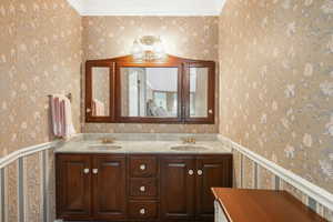 Owners en suite bathroom featuring crown molding and dual bowl vanity, folding mirrors