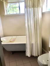 Bathroom featuring breakfast area, tile patterned floors, a washtub, and toilet