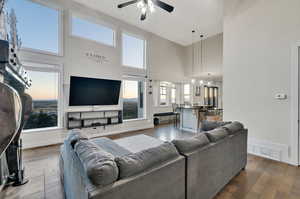 Living room featuring ceiling fan, a towering ceiling, plenty of natural light, and hardwood / wood-style floors