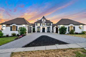 French country inspired facade with a garage and a yard