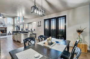 Dining room featuring hardwood / wood-style floors, sink, a high ceiling, and ceiling fan with notable chandelier