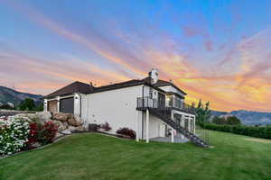 Back house at dusk featuring a yard, a mountain view, and a garage