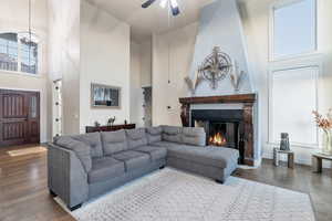 Living room featuring ceiling fan with notable chandelier, a towering ceiling, and wood-type flooring