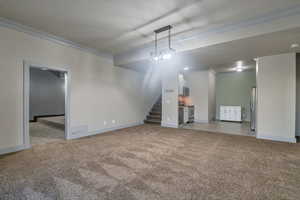 Unfurnished living room featuring crown molding and carpet flooring