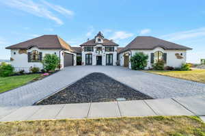 French country inspired facade featuring a front yard and a garage