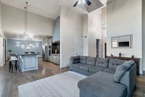 Living room with dark wood-type flooring, sink, a high ceiling, and ceiling fan