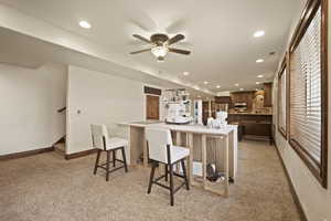 Kitchen with light carpet, a large island, ceiling fan, and a kitchen bar