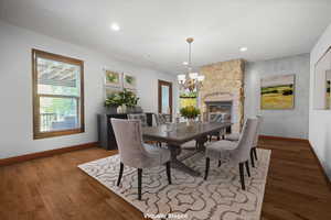 Virtually Staged: Dining area featuring a stone fireplace, hardwood / wood-style flooring, and a chandelier