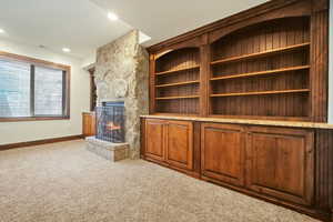 Unfurnished living room with a stone fireplace and carpet