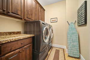 Laundry area with washer and dryer, cabinets, and light tile floors