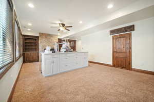 Kitchen with light carpet, white cabinets, and ceiling fan