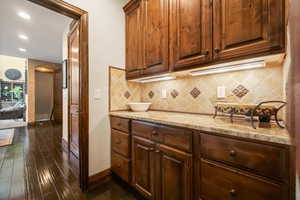 Kitchen featuring tasteful backsplash, dark hardwood / wood-style floors, and light stone counters