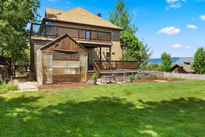 Rear view of property featuring a balcony, a mountain view, and a yard