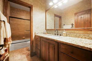 Full bathroom featuring tile flooring, vanity, toilet, and enclosed tub / shower combo