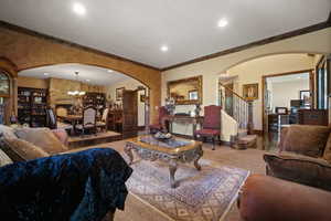 Carpeted living room featuring ornamental molding and a chandelier