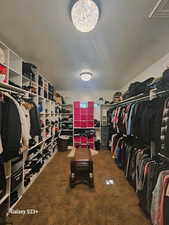 Walk in closet featuring a chandelier and carpet floors