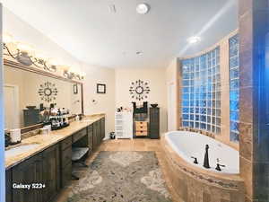 Bathroom with tiled tub, dual bowl vanity, and tile patterned flooring