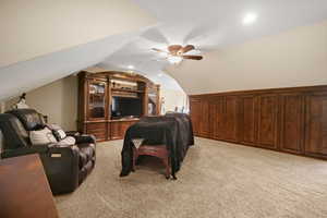 Interior space with light colored carpet, ceiling fan, and lofted ceiling