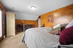 Bedroom featuring lofted ceiling and light carpet