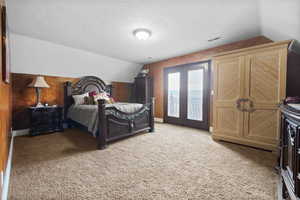 Bedroom featuring french doors, a textured ceiling, light colored carpet, access to exterior, and lofted ceiling