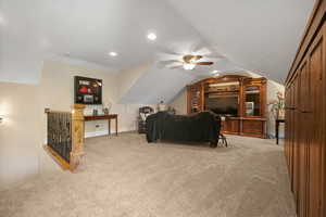 Living room with carpet, ceiling fan, and lofted ceiling