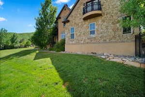 View of home's exterior with a yard and a balcony