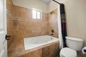 Bathroom with shower / bathtub combination with curtain and toilet