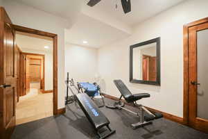 Workout room featuring ceiling fan and light tile floors