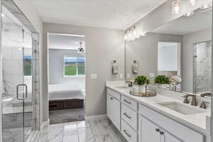 Bathroom with dual bowl vanity, tile flooring, walk in shower, and a textured ceiling