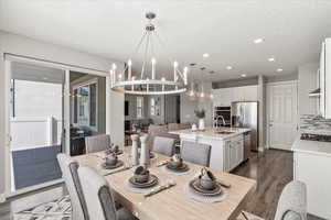 Dining room with an inviting chandelier, sink, a textured ceiling, and dark hardwood / wood-style floors