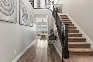 Stairs with a towering ceiling, wood-type flooring, and ceiling fan