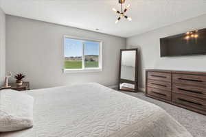 Bedroom featuring carpet floors, a textured ceiling, and an inviting chandelier