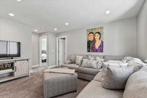 Living room featuring dark colored carpet and a textured ceiling