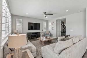 Living room with ceiling fan, a textured ceiling, and hardwood / wood-style flooring