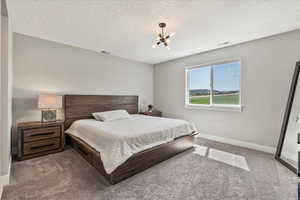 Bedroom featuring carpet flooring, a notable chandelier, and a textured ceiling