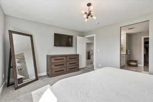 Bedroom with an inviting chandelier, light carpet, and ensuite bath