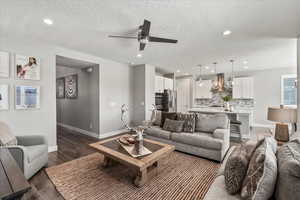 Living room featuring ceiling fan, a textured ceiling, and hardwood / wood-style flooring