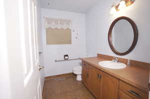 1/2 Bathroom featuring tile floors, toilet, and vanity with extensive cabinet space