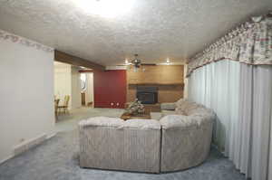 Living room with a textured ceiling, a fireplace, and carpet floors