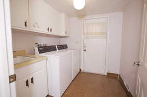 Laundry chute from master Washroom featuring separate washer and dryer, tile flooring, cabinets, washer hookup, and sink