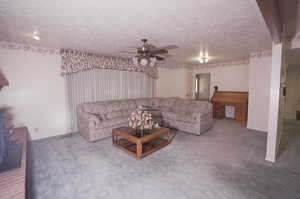 Carpeted living room featuring ceiling fan and a textured ceiling