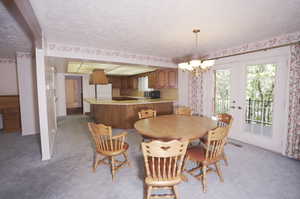 Carpeted dining room with a chandelier, a textured ceiling, and french doors