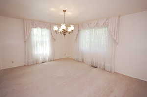 Carpeted empty room with an inviting chandelier